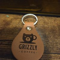Custom leather teardrop keychain with engraved bear coffee cup logo – Grizzly Coffee design